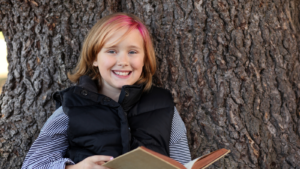 girl next to tree with a book