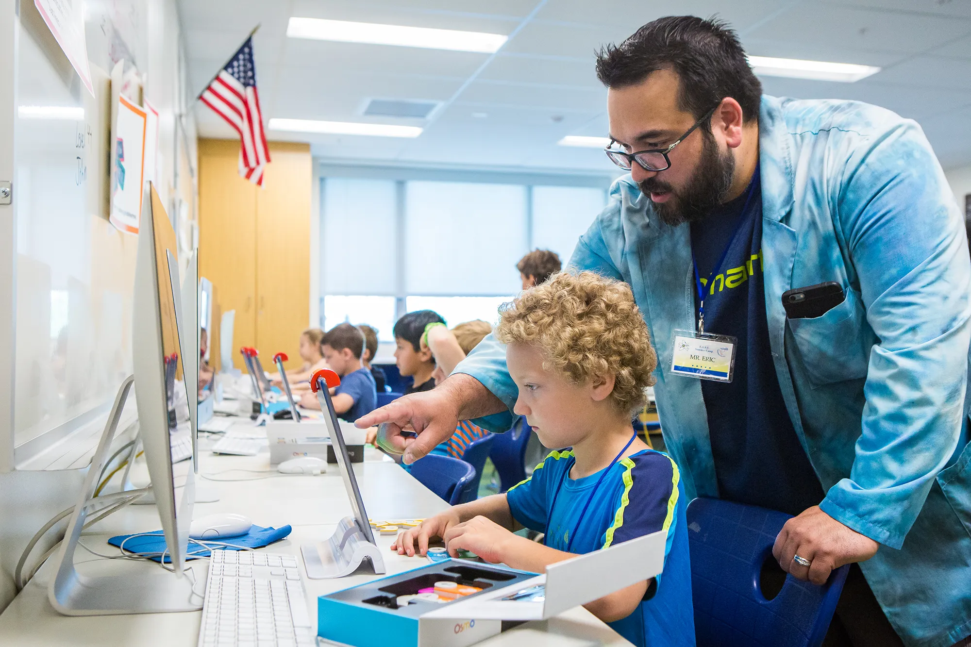 teacher points at computer with student
