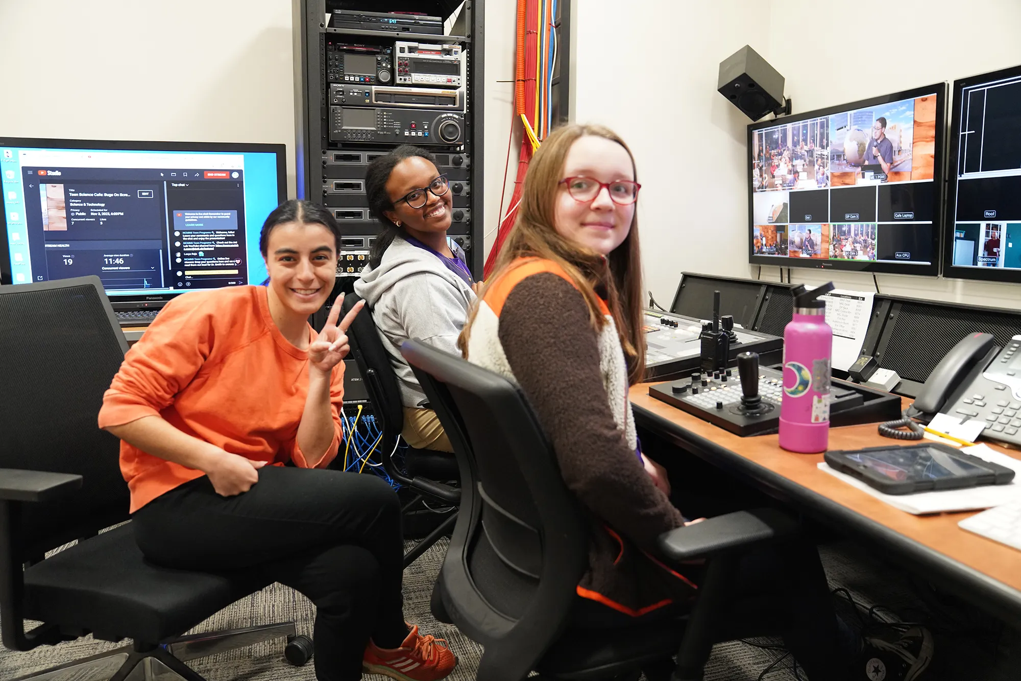 three kids smile by computer