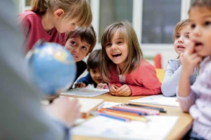 students sit at table interacting with globe