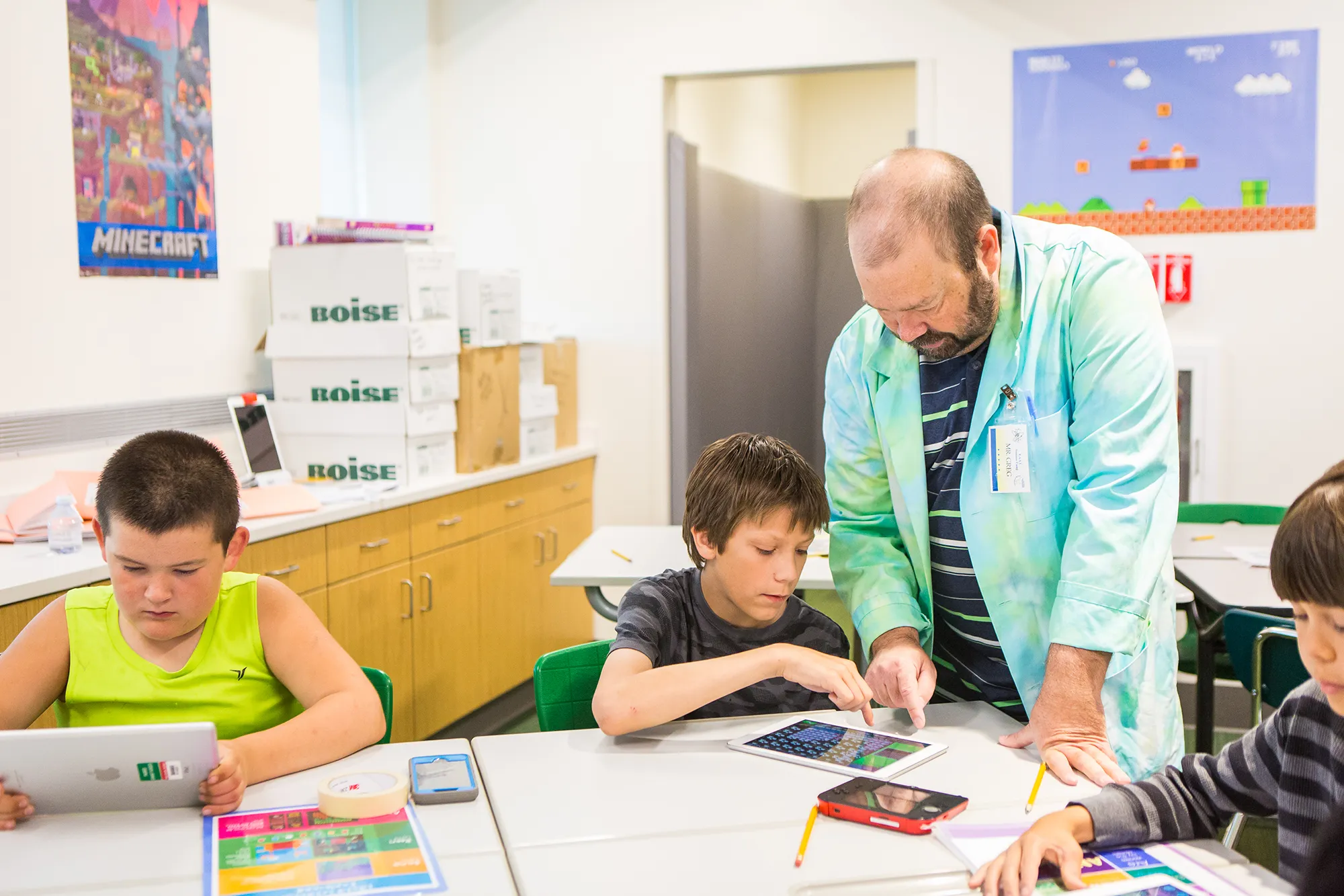 teacher stands with student at table instructing