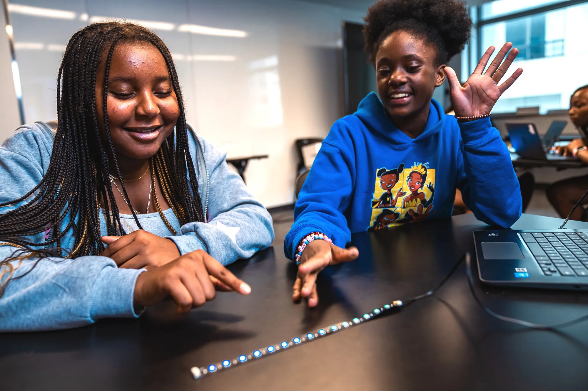 two girls smiling over LED lights