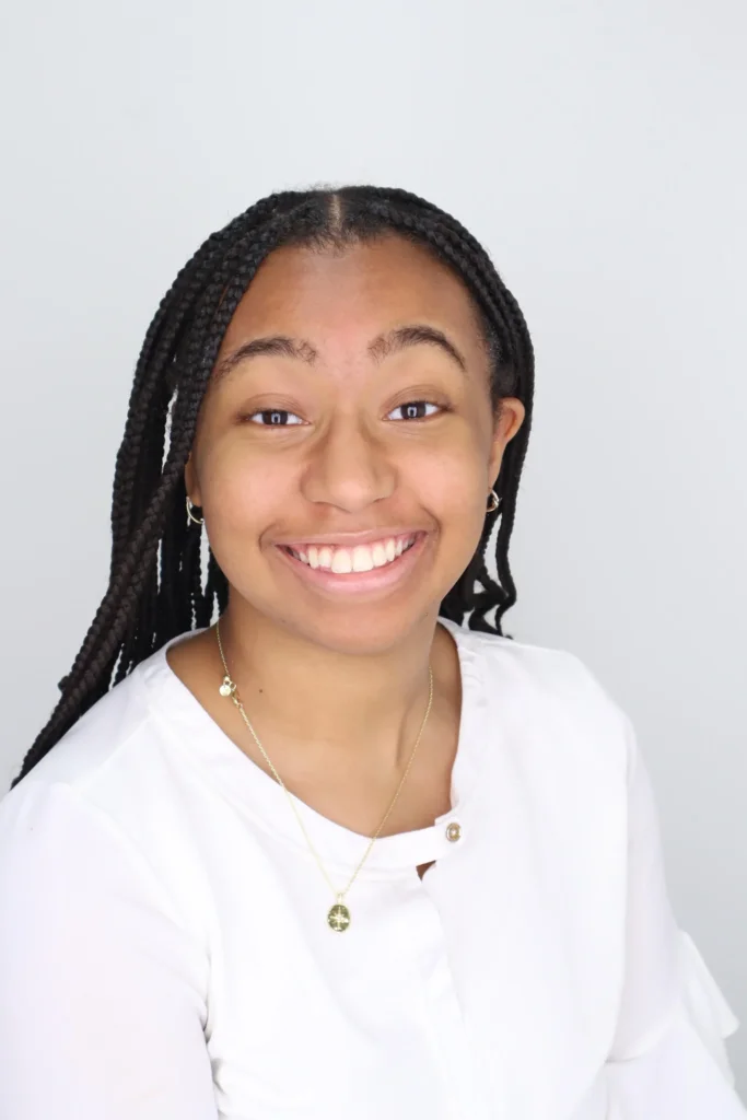 A girl of color smiling with white shirt