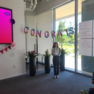 girl poses in front of balloons that say congrats