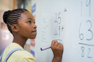 Girl solving mathematical equation on a white board