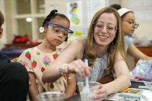 A young girl and teacher look at a solution during a science experiment.