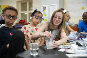 A student watches as a teacher stirs a concoction during a science experiment.