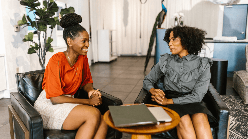 Two women sitting in armchairs facing each other and having a conversation.